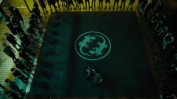 Movie still from “Fahrenheit 451” (2018), directed by Ramin Bahrani – A man kneeling on the ground in front of a group of onlookers; Extreme Wide shot, Overhead angle