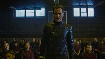 Movie still from “Fahrenheit 451” (2018), directed by Ramin Bahrani – A man in a black jacket standing in front of a group of people; Medium shot, Low angle