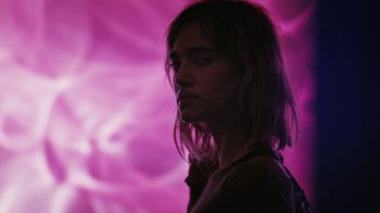 Movie still from “Fahrenheit 451” (2018), directed by Ramin Bahrani – A woman is standing in front of a purple background; Close Up shot, Low angle
