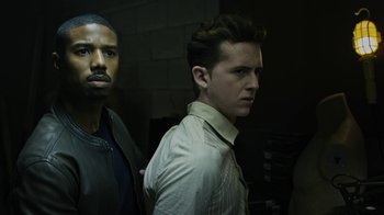 Movie still from “Fahrenheit 451” (2018), directed by Ramin Bahrani – Two men standing next to each other in a dark room; Medium shot, High angle