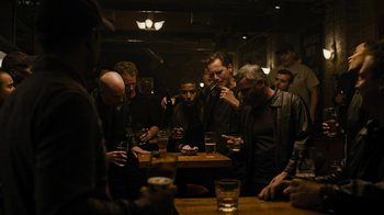 Movie still from “Fahrenheit 451” (2018), directed by Ramin Bahrani – A group of men sitting around a table with glasses of beer; Wide shot, High angle