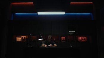 Movie still from “Fahrenheit 451” (2018), directed by Ramin Bahrani – A man sitting at a desk in a dark room; Wide shot, Low angle