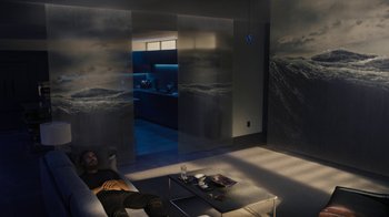 Movie still from “Fahrenheit 451” (2018), directed by Ramin Bahrani – A man laying on a couch in a living room; Extreme Wide shot, High angle
