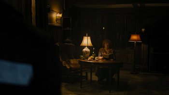 Movie still from “Fahrenheit 451” (2018), directed by Ramin Bahrani – A woman sitting at a table reading a book; Wide shot, High angle