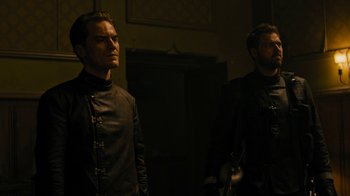 Movie still from “Fahrenheit 451” (2018), directed by Ramin Bahrani – Two men standing next to each other in a dark room; Medium shot, Low angle