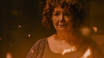 Movie still from “Fahrenheit 451” (2018), directed by Ramin Bahrani – An older woman with curly red hair is looking at the camera; Close Up shot, High angle