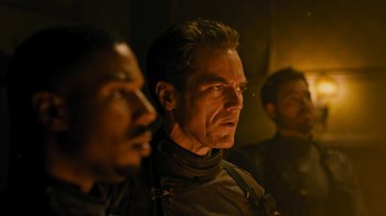 Movie still from “Fahrenheit 451” (2018), directed by Ramin Bahrani – A group of men standing next to each other in a dark room; Close Up shot, Over the shoulder angle