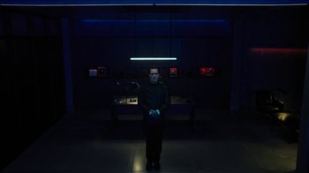 Movie still from “Fahrenheit 451” (2018), directed by Ramin Bahrani – A man standing in a dark room at night; Wide shot, High angle