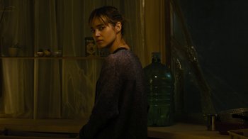 Movie still from “Fahrenheit 451” (2018), directed by Ramin Bahrani – A woman standing next to a green water bottle; Medium shot, Over the shoulder angle