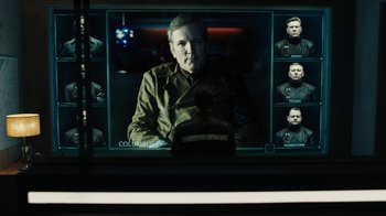 Movie still from “Fahrenheit 451” (2018), directed by Ramin Bahrani – A man in a military uniform sitting in front of a television; Medium shot, Over the shoulder angle