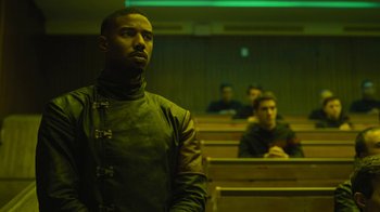 Movie still from “Fahrenheit 451” (2018), directed by Ramin Bahrani – A man standing in front of a group of people in an auditorium; Medium shot, Over the shoulder angle