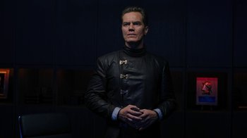 Movie still from “Fahrenheit 451” (2018), directed by Ramin Bahrani – A man in a black jacket is standing in a dark room; Medium shot, Low angle