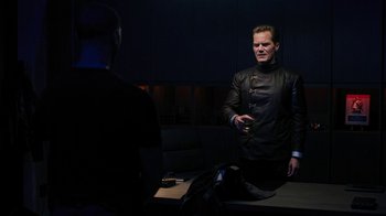 Movie still from “Fahrenheit 451” (2018), directed by Ramin Bahrani – A man standing in front of another man in a dark room; Medium shot, Over the shoulder angle