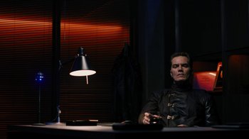 Movie still from “Fahrenheit 451” (2018), directed by Ramin Bahrani – A man sitting at a table in front of a lamp; Medium shot, Low angle