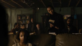 Movie still from “Fahrenheit 451” (2018), directed by Ramin Bahrani – A group of people sitting in a living room; Medium shot, Over the shoulder angle