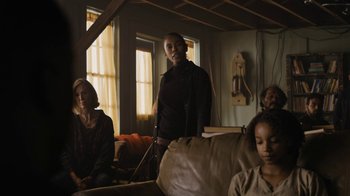 Movie still from “Fahrenheit 451” (2018), directed by Ramin Bahrani – A group of people sitting in a living room next to each other; Medium shot, Low angle