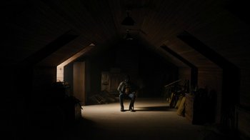 Movie still from “Fahrenheit 451” (2018), directed by Ramin Bahrani – A man sitting in the middle of an attic; Wide shot, High angle