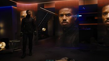 Movie still from “Fahrenheit 451” (2018), directed by Ramin Bahrani – A man standing in front of a large portrait of a man; Medium shot, Over the shoulder angle