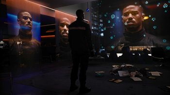 Movie still from “Fahrenheit 451” (2018), directed by Ramin Bahrani – A man standing in front of a large picture of a man; Wide shot, Over the shoulder angle
