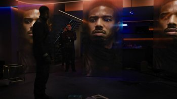Movie still from “Fahrenheit 451” (2018), directed by Ramin Bahrani – Two men standing in front of a large poster of a man's face; Medium shot, Over the shoulder angle