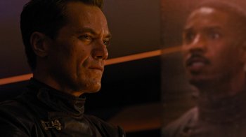 Movie still from “Fahrenheit 451” (2018), directed by Ramin Bahrani – A person wearing a suit and tie; Close Up shot, Over the shoulder angle