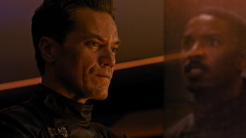 Movie still from “Fahrenheit 451” (2018), directed by Ramin Bahrani – A person wearing a suit and tie; Close Up shot, Over the shoulder angle