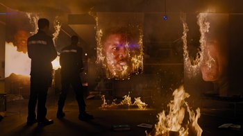 Movie still from “Fahrenheit 451” (2018), directed by Ramin Bahrani – A man standing in front of a fire with flames coming out of it; Medium shot, Over the shoulder angle