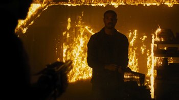 Movie still from “Fahrenheit 451” (2018), directed by Ramin Bahrani – A man standing in front of a burning building; Medium shot, Over the shoulder angle
