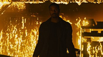 Movie still from “Fahrenheit 451” (2018), directed by Ramin Bahrani – A man standing in front of a burning building; Medium shot, Low angle
