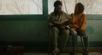 Movie still from “Fast Color” (2018), directed by Julia Hart – A woman sitting on a bench reading a book to a young girl; Medium shot, Over the shoulder angle