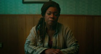 Movie still from “Fast Color” (2018), directed by Julia Hart – A woman sitting in front of a wooden wall; Medium shot, High angle