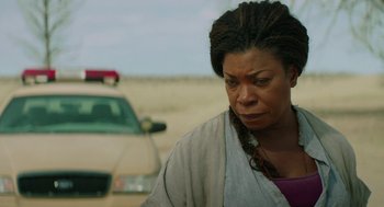 Movie still from “Fast Color” (2018), directed by Julia Hart – A woman standing in the middle of a road near a police car; Close Up shot, Over the shoulder angle