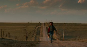 Movie still from “Fast Color” (2018), directed by Julia Hart – A man walking down a dirt road holding a skateboard; Wide shot, Low angle