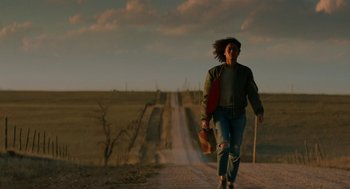 Movie still from “Fast Color” (2018), directed by Julia Hart – A woman walking down a dirt road holding a skateboard; Wide shot, Low angle