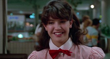 Movie still from “Fast Times at Ridgemont High” (1982), directed by Amy Heckerling – A woman with a bow tie smiles for the camera; Close Up shot, Over the shoulder angle