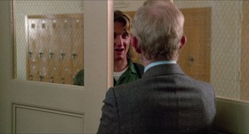 Movie still from “Fast Times at Ridgemont High” (1982), directed by Amy Heckerling – A man in a suit is talking to another man in a green shirt; Medium shot, Over the shoulder angle