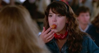 Movie still from “Fast Times at Ridgemont High” (1982), directed by Amy Heckerling – A woman is eating a donut while sitting at a table; Close Up shot, Over the shoulder angle