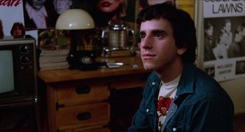 Movie still from “Fast Times at Ridgemont High” (1982), directed by Amy Heckerling – A man sitting in front of a desk in a room; Close Up shot, Low angle