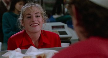 Movie still from “Fast Times at Ridgemont High” (1982), directed by Amy Heckerling – A woman in a red shirt is smiling at the camera; Close Up shot, Over the shoulder angle
