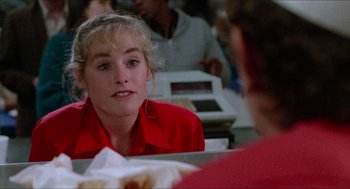 Movie still from “Fast Times at Ridgemont High” (1982), directed by Amy Heckerling – A woman sitting at a table in front of a plate of food; Close Up shot, Over the shoulder angle