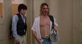 Movie still from “Fast Times at Ridgemont High” (1982), directed by Amy Heckerling – A man with a donut in his mouth and another man with a shoe in his hand; Medium shot, Low angle