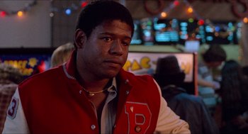 Movie still from “Fast Times at Ridgemont High” (1982), directed by Amy Heckerling – A man in a red and white jacket sitting at a table; Close Up shot, Over the shoulder angle