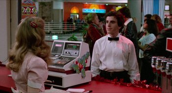 Movie still from “Fast Times at Ridgemont High” (1982), directed by Amy Heckerling – A man sitting at a table in front of a cash register; Medium shot, Over the shoulder angle