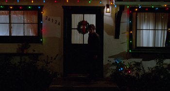 Movie still from “Fast Times at Ridgemont High” (1982), directed by Amy Heckerling – A man standing in front of a door with a wreath on it; Wide shot, Low angle