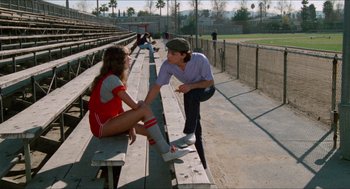 Movie still from “Fast Times at Ridgemont High” (1982), directed by Amy Heckerling – A woman sitting on a bench next to a skateboarder; Wide shot, Over the shoulder angle