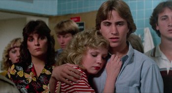 Movie still from “Fast Times at Ridgemont High” (1982), directed by Amy Heckerling – A man and a woman hugging in front of a group of other people; Close Up shot, Low angle