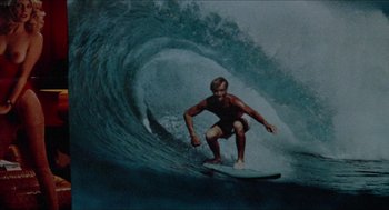 Movie still from “Fast Times at Ridgemont High” (1982), directed by Amy Heckerling – A man riding a wave on top of a surfboard in the ocean; Medium shot, Low angle