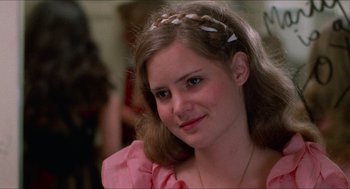 Movie still from “Fast Times at Ridgemont High” (1982), directed by Amy Heckerling – A young woman wearing a pink shirt and a headband; Close Up shot, Over the shoulder angle
