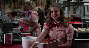 Movie still from “Fast Times at Ridgemont High” (1982), directed by Amy Heckerling – A woman holding a tray of hot dogs in front of another woman; Medium shot, Low angle