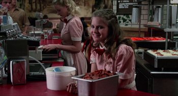 Movie still from “Fast Times at Ridgemont High” (1982), directed by Amy Heckerling – A woman sitting at a table with a tray of food; Medium shot, Over the shoulder angle